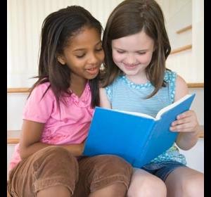 A little white girl reading with a little black girl