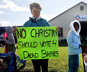 a protestor holding a sign: no christian should vote 4 dead babies