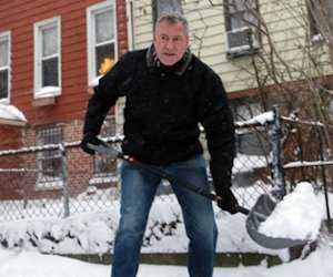 An old man shovelling snow